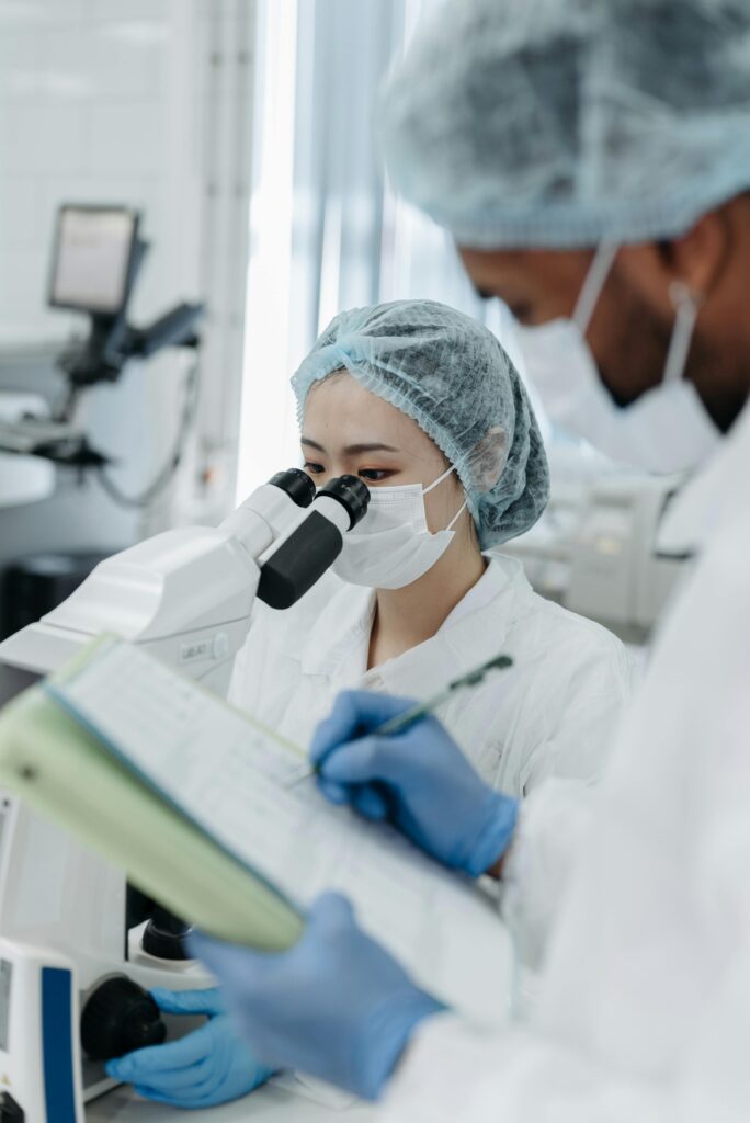 pexels-photo-8442153-8442153 Two scientists in protective gear performing research with a microscope in a modern laboratory.